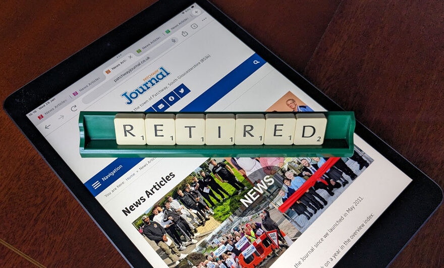 Photo of letter tiles spelling the word 'Retired' in a rack placed over a webpage displayed on an iPad.